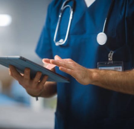 Hospital Ward: Unrecognizable Head Nurse, Doctor, Surgeon Uses Digital Tablet Computer Health Care Vitals Monitoring Computer Machine. Modern Clinic with Advanced Equipment and Professional Working